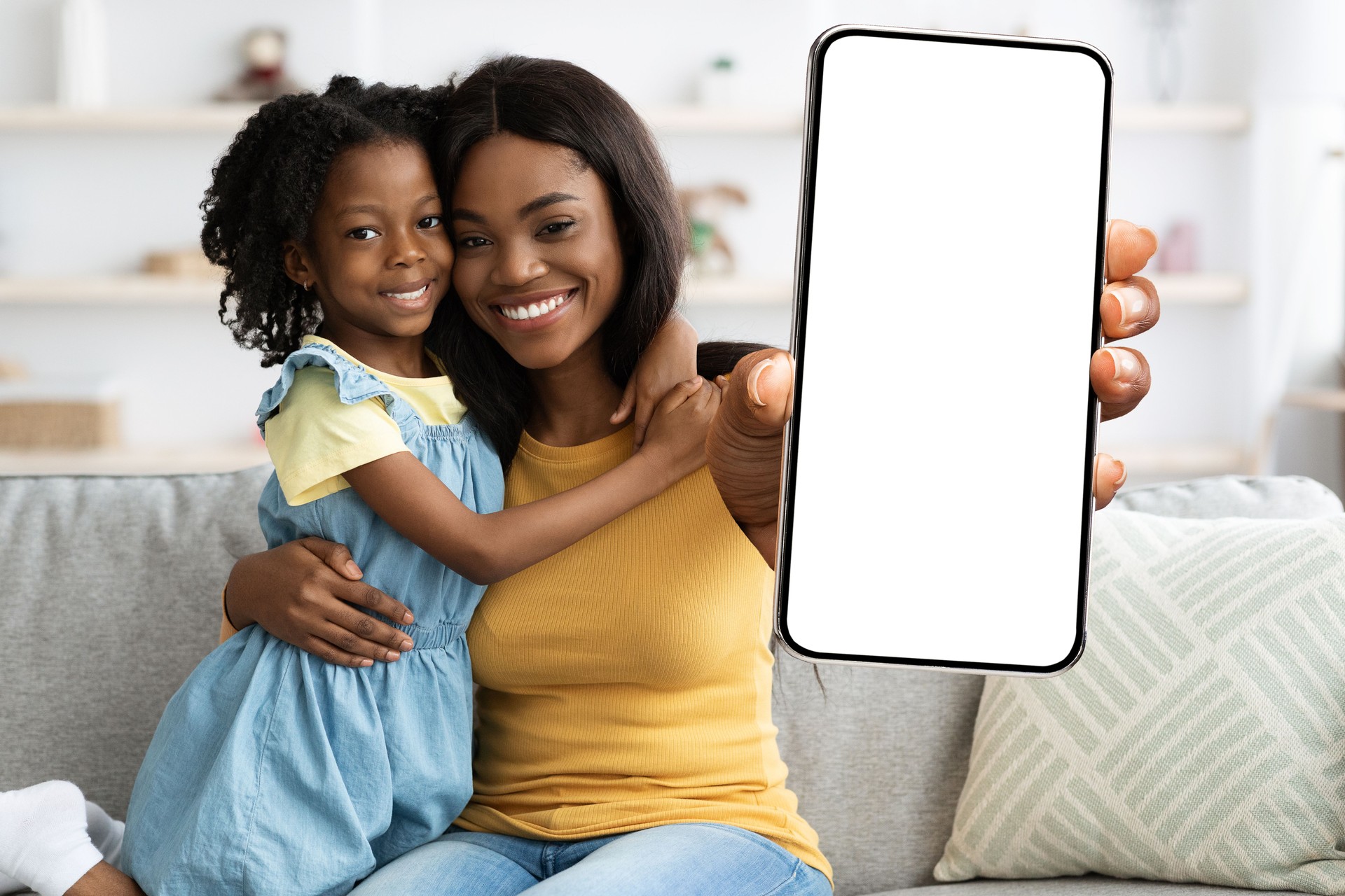 Family Offer. African American Mom And Daughter Showing Blank Smartphone At Camera